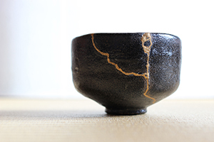 Black teacup with gold threads holding it together