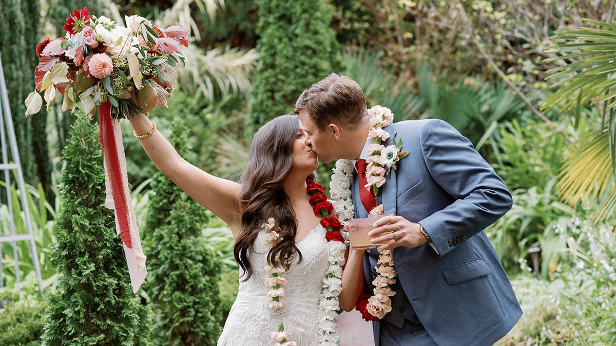 A bride and groom pose with a man, woman and two children in a garden.