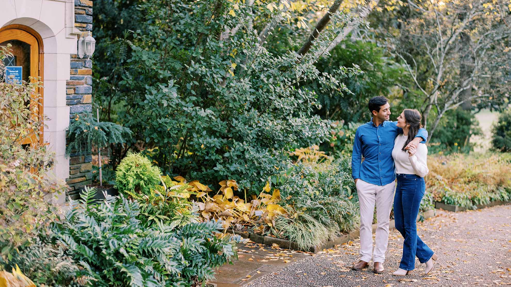 A man and a woman walk down a garden pathway in the Terrace Gardens. The man has his arm around the woman.