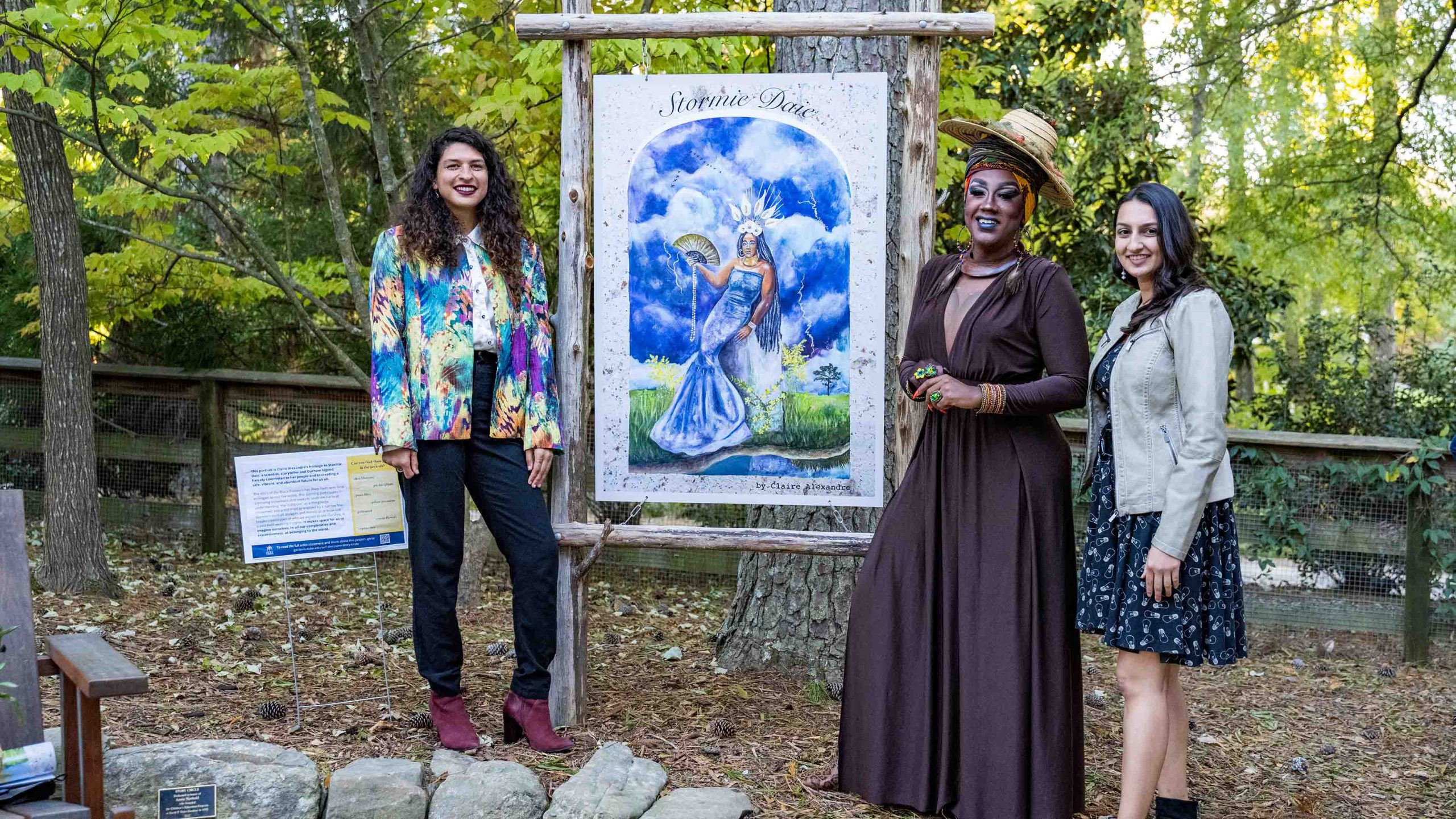 Amal Dadi, Claire Alexandre and Stormie Daie stand in front of a portrait