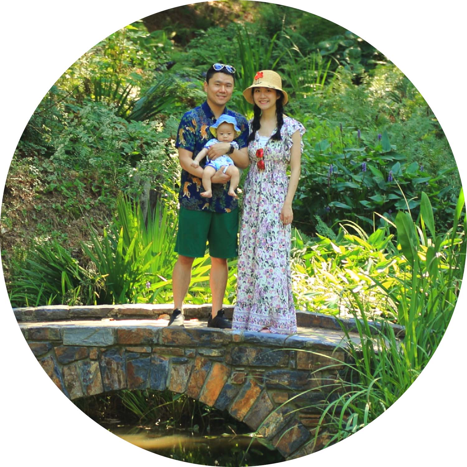 A family with a small baby poses for a photo on a stone bridge.